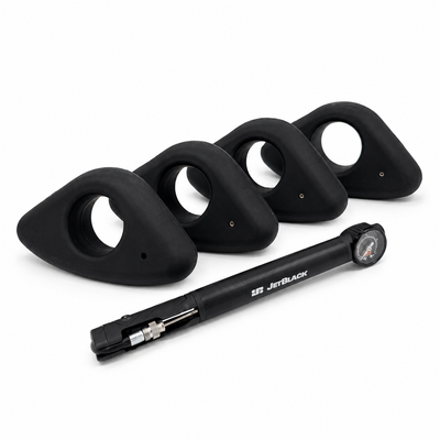 Four black silicone strap covers arranged in a row with a black pump tube in front, photographed on a clean white background. The pump tube has the brand name 'JETBLACK' printed on it.