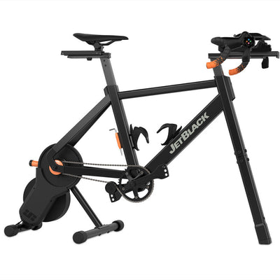 JetBlack indoor cycling trainer on a white background, featuring a black frame with white branding, a black saddle, and orange accent details.